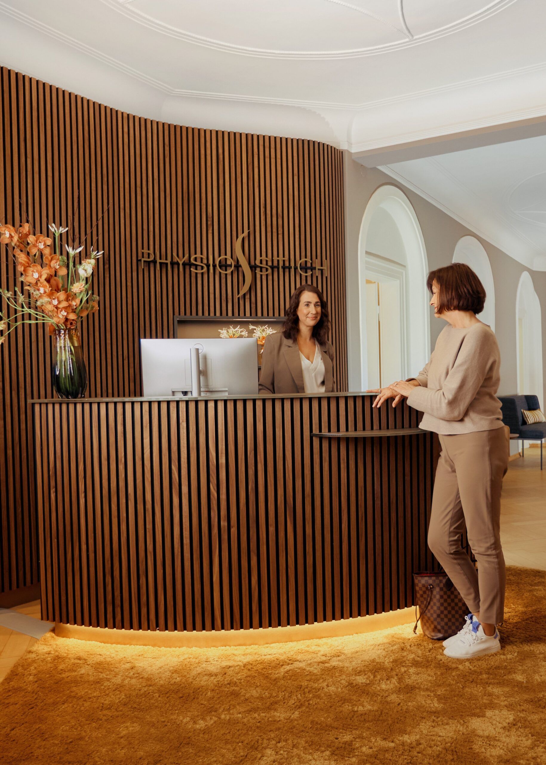 Physiotherapie in München Schwabing, Patientin an der Anmeldung zur Terminvereinbarung, Praxis mit luxuriöser Ausstattung