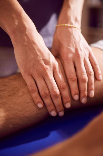 Physiotherapeutin behandelt das Knie eines Patienten
