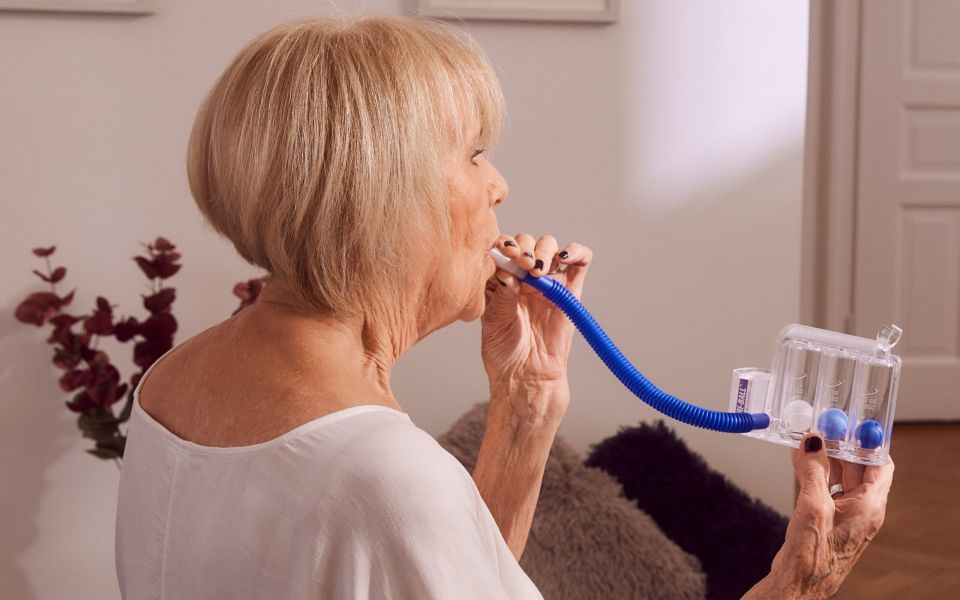 Ältere Patientin verbessert zu Hause Ihre Atmung mittels Atemtherapie und Physiotherapie mit einem Atemtrainer