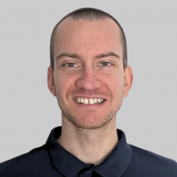 Ein lächelnder Mann trägt ein dunkelblaues Hemd.