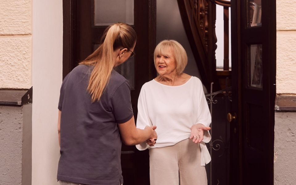 Physiotherapie Hausbesuch, Patientin empfängt Physiotherapeutin bei sich zu Hause