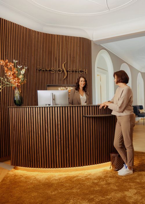 Physiotherapie in München Schwabing, Patientin an der Anmeldung zur Terminvereinbarung, Praxis mit luxuriöser Ausstattung