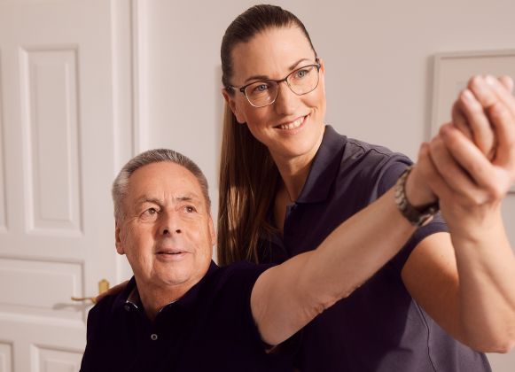 Patient macht Krankengymnastik auf neurophysiologischer Grundlage mit Physiotherapeutin