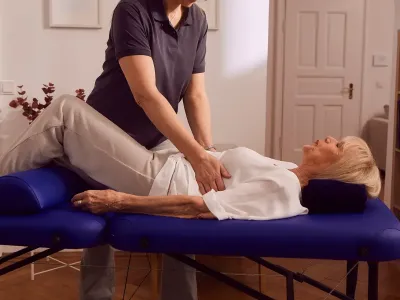 Physiotherapeutin behandelt Patientin auf Liege im hellen Raum.