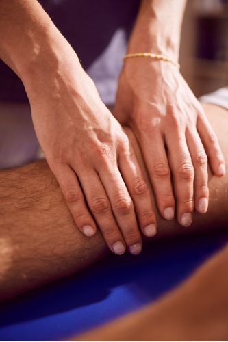 Physiotherapeutin behandelt das Knie eines Patienten