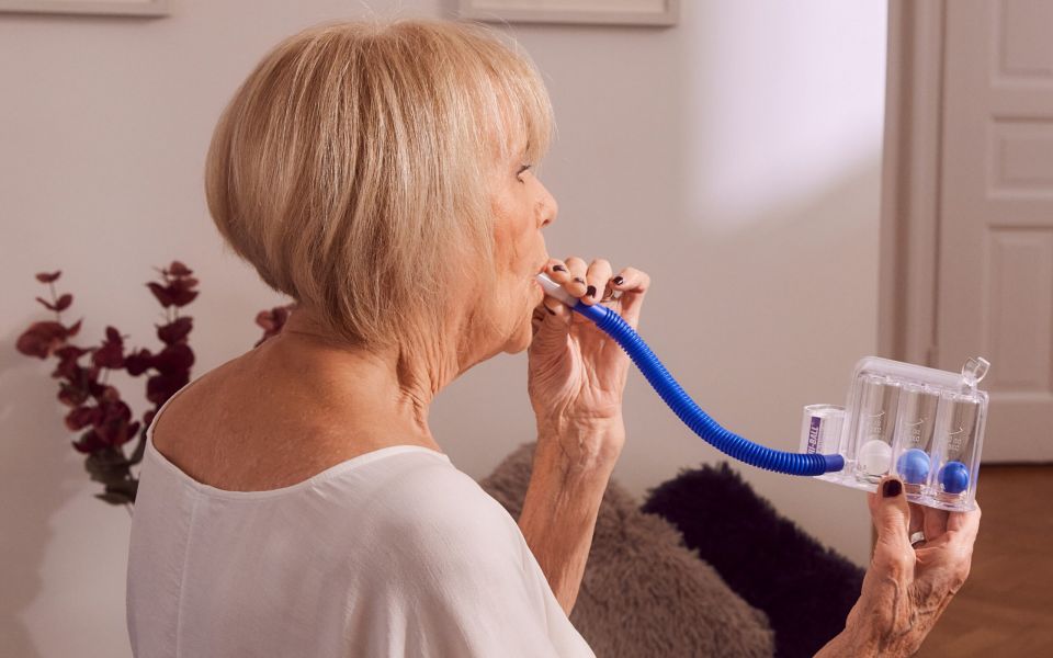 Ältere Patientin verbessert zu Hause Ihre Atmung mittels Atemtherapie und Physiotherapie mit einem Atemtrainer